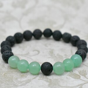 Könnte beinhalten: Ein Armband aus schwarzen Lavasteinen und grünen Jadeperlen. Das Armband besteht aus einer Mischung aus schwarzen und grünen Perlen.