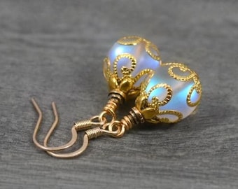 May include: A pair of iridescent blue glass earrings with gold filigree detailing and gold hooks.