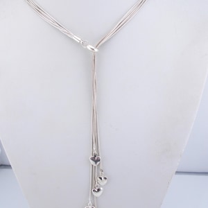 May include: A silver necklace with multiple strands and a dangling charm of five small silver hearts.