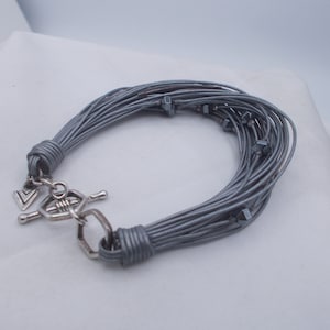 May include: A grey multi-strand bracelet with a silver clasp and small grey beads.