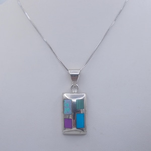May include: A silver necklace with a rectangular pendant featuring four inlaid stones: turquoise, green, purple, and blue.