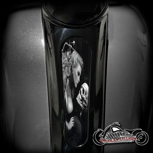 Könnte beinhalten: Schwarzweiß-Illustration einer Frau mit langen Haaren, die einen Schädel betrachtet. Das Bild ist auf schwarzem Hintergrund mit silbernem Rand.