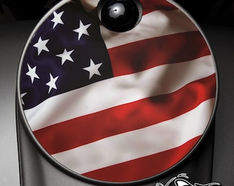 May include: A round, black gas cap with a sticker of the American flag. The flag is red, white, and blue and has a wavy, flowing design. The text "AMERICAN FREEDOM" is printed below the gas cap.
