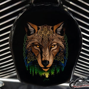 May include: A black motorcycle air cleaner cover with a colorful graphic of a wolf's head with a Celtic cross and knotwork design. The wolf's eyes are yellow, and the background is a forest scene.