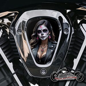 Könnte beinhalten: Ein schwarzes Motorrad mit einem verchromten Lufteinlass. Der Lufteinlass hat einen Ausschnitt, der eine Frau mit einem Zucker Schädel Make-up Design zeigt. Sie trägt eine schwarze Lederjacke und einen schwarzen Spitzen-BH. Das Motorrad hat die Worte "American Freedom" unten aufgedruckt.