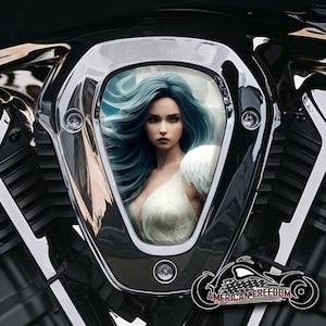 Könnte beinhalten: Ein Motorrad-Lufteinlassabdeckung mit Chrom-Finish und einem dekorativen Bild einer Frau mit langen blauen Haaren und einem weißen Kleid. Das Bild ist von einem weißen Rahmen umgeben.