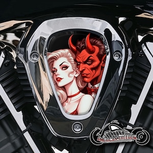 Puede incluir: Una cubierta de motor de motocicleta cromada con una ilustración estilizada de un diablo y una mujer. El diablo es rojo con cuernos y pajarita, la mujer tiene cabello rubio y lápiz labial rojo. El texto "AMERICAN FREEDOM" es visible.