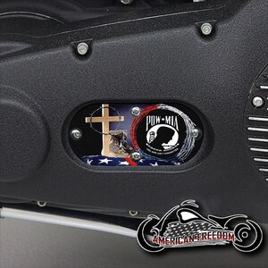 Może przedstawiać: Czarny element motocykla z czerwono-biało-niebieskim emblematem POW MIA z krzyżem i sylwetką żołnierza. Tekst brzmi "Nie jesteś zapomniany".