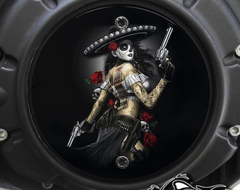May include: A black motorcycle cover with a round, black, skull-themed graphic. The graphic features a woman with a sugar skull face wearing a sombrero and holding two pistols. The background is black with red roses.
