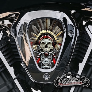 Könnte beinhalten: Ein verchromter Motorradluftfilter mit einem Totenkopf, der einen indianischen Kopfschmuck trägt. Der Totenkopf ist von einem rot-weiß-schwarzen Design umgeben. Der Text "AMERICAN FREEDOM" ist am unteren Rand des Bildes sichtbar.