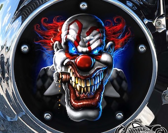 May include: A black and white motorcycle cover with a scary clown face graphic. The clown has red hair, blue eyes, and a red nose. The clown is smoking a cigar and has a menacing grin. The cover has a black background and a silver border.
