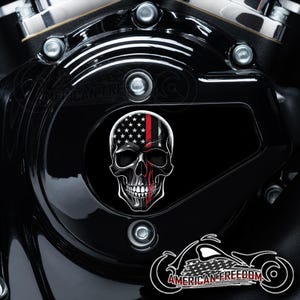 May include: A black motorcycle engine cover with a skull graphic. The skull is half covered with an American flag and a red stripe. The text "AMERICAN FREEDOM" is visible at the bottom of the image.