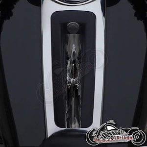 May include: A black motorcycle gas tank with a chrome trim and a black and white graphic of a hooded figure holding a sword.