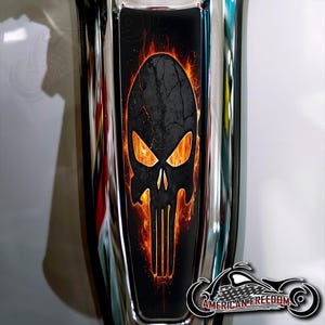 May include: A black skull graphic with orange flames, set against a black background. The design is on a chrome surface, with the words "AMERICAN FREEDOM" and a motorcycle logo in the bottom right corner.