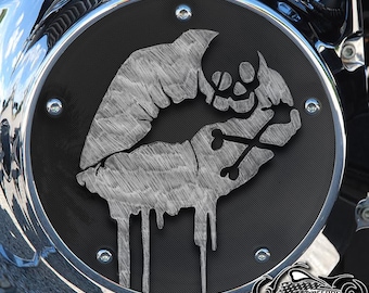 May include: A black motorcycle air cleaner cover with a silver skull and lips design. The skull is holding crossed bones and the lips are dripping with silver paint.