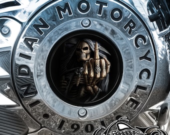 May include: A chrome motorcycle engine cover with the words "INDIAN MOTORCYCLE" in a circular pattern. The center features a detailed image of the Grim Reaper giving the middle finger. The bottom of the cover reads "1901" and has a logo that says "AMERICAN FREEDOM".