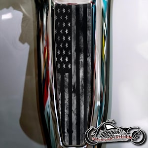 May include: A black and white distressed American flag decal with a white star pattern. The decal is applied to a chrome motorcycle part.