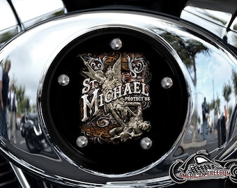 May include: A chrome motorcycle air cleaner cover with a black background featuring a graphic of Saint Michael with the words "St. Michael Protect Us".