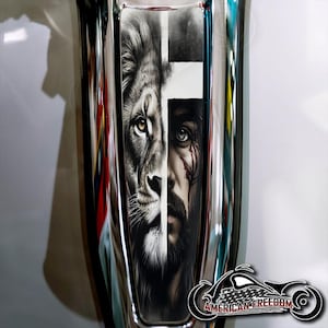 May include: A black and white graphic design featuring a lion and a man's face, with a white cross in the middle. The image is on a silver background.