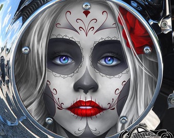 May include: A circular chrome motorcycle derby cover featuring a detailed graphic of a face with white sugar skull makeup, bright blue eyes, red lips, and a red rose tucked into white hair, framed by a polished metallic border with bolts.