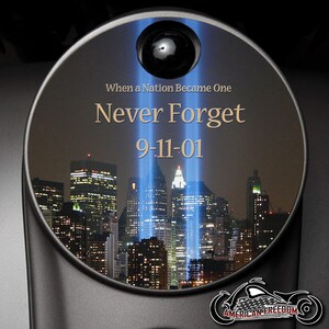 May include: A commemorative disc with the text "Never Forget 9-11-01" and an image of the New York City skyline with the Tribute in Light. The disc also features the words "When a Nation Became One" and the "American Freedom" logo.