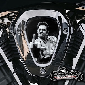 Könnte beinhalten: Ein schwarzer und verchromter Motorradeinlass mit einem Schwarzweißbild eines Mannes, der den Mittelfinger zeigt. Das Bild ist in einer Ausschnittform und der Text "AMERICAN FREEDOM" befindet sich unter dem Bild.