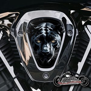Könnte beinhalten: Ein schwarzer Panther-Grafik-Luftansaugabdeckung für ein Motorrad. Die Abdeckung ist aus Chrom und hat ein schwarzes Panther-Design mit gelben Augen.