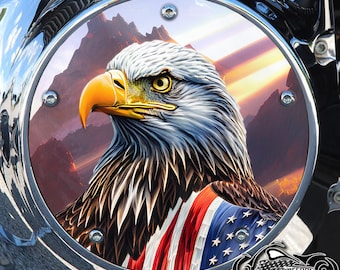 May include: A circular chrome motorcycle derby cover featuring a detailed illustration of a bald eagle with a yellow beak. The eagle is draped in an American flag pattern with red, white, and blue stripes and stars. The background shows mountains.