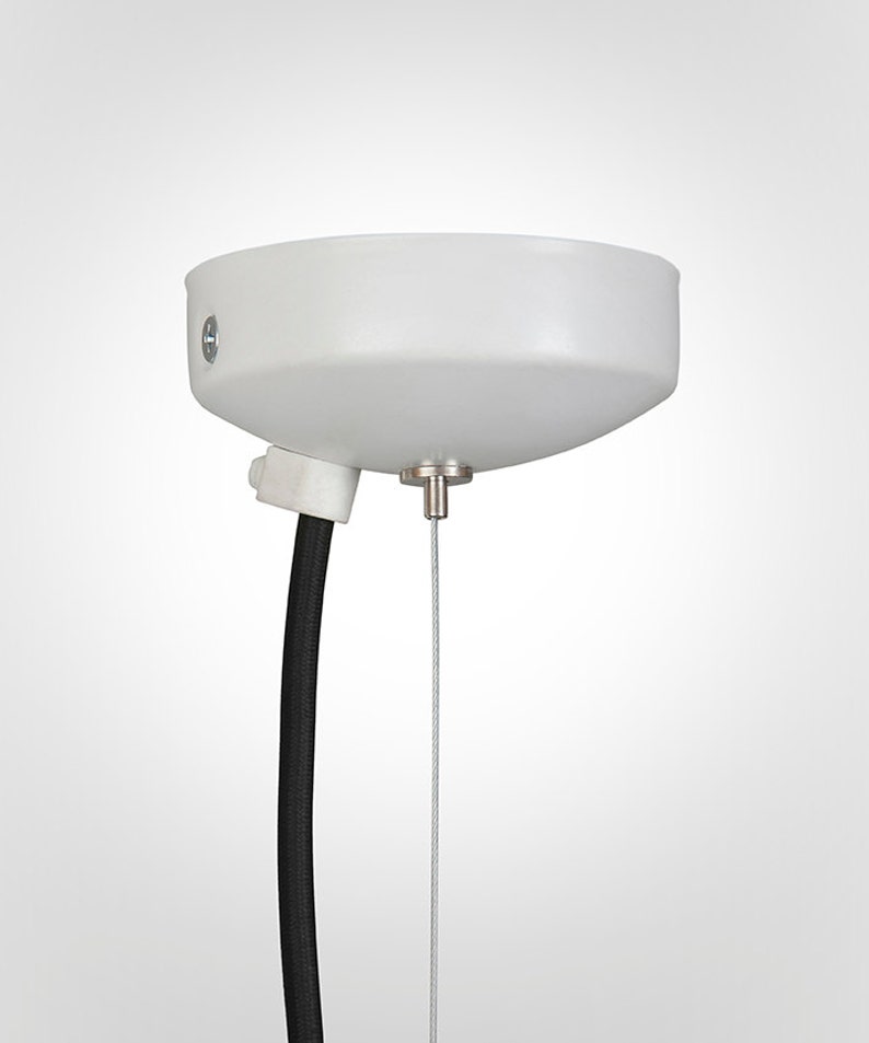 May include: White ceiling mount with a black wire and a silver cable hanging down.