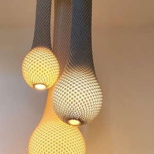 May include: Three hanging light fixtures with a woven, net-like design. The fixtures are shaped like teardrops and are illuminated with warm, yellow light.