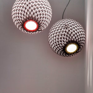 May include: Two hanging pendant lights with a woven, textured, brown and white pattern. The lights are round and have a white lightbulb inside.