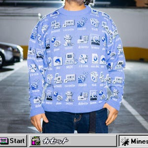 Puede incluir: Un suéter azul claro con un patrón repetido de iconos y texto de ordenador retro. Los iconos incluyen disquetes, ordenadores y carpetas. El suéter tiene cuello redondo y mangas largas. La parte inferior del suéter tiene el texto "Start" y "Mines".