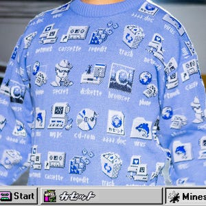 May include: A light blue sweater with a repeating pattern of retro computer icons and text. The icons include a floppy disk, a computer monitor, and a trash can. The text includes the words "network", "cassette", and "virus".