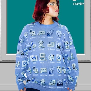 May include: A light blue long-sleeve knit sweater featuring a repeating pattern of white and dark blue pixelated computer icons and text labels including network, cassette, regedit, trash, secret, diskette, browser, virus, my pc, and cd-rom.