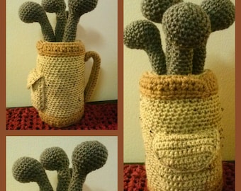 May include: A crocheted golf bag with four golf clubs sticking out of the top. The bag is beige and the clubs are grey.