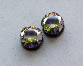 May include: A pair of iridescent green and purple gemstone earrings with black metal settings.