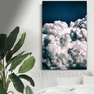 May include: A photograph of a white fluffy cloud formation against a deep blue sky. The clouds are large and puffy, filling the entire frame. The image is taken from a low angle, giving the viewer a sense of being surrounded by the clouds.