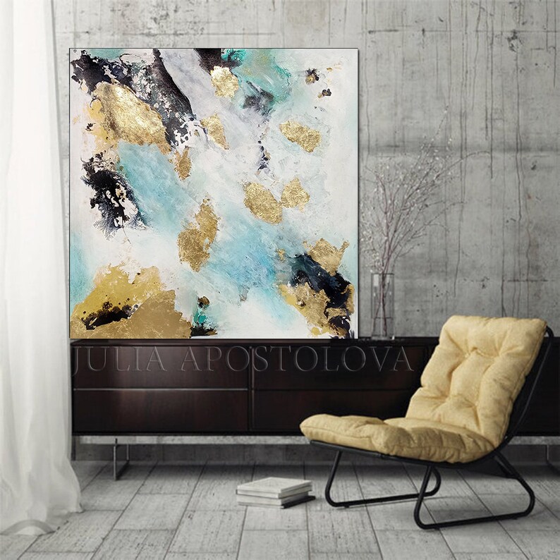 May include: Abstract painting with gold leaf accents on a white canvas. The painting features shades of blue, black, and gold. The painting is hanging on a wall in a modern interior.