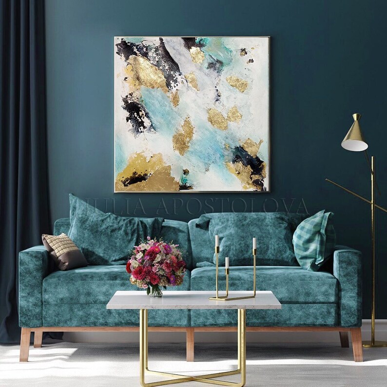 May include: Abstract painting with gold and teal accents on a white canvas. The painting is hanging on a teal wall above a teal velvet sofa with gold accents.