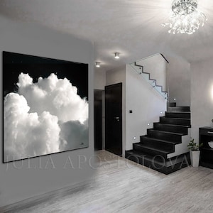 May include: Large black and white cloud art print. The artwork features a dramatic image of fluffy white clouds against a dark background. The print is displayed in a modern interior setting, enhancing the room's aesthetic.