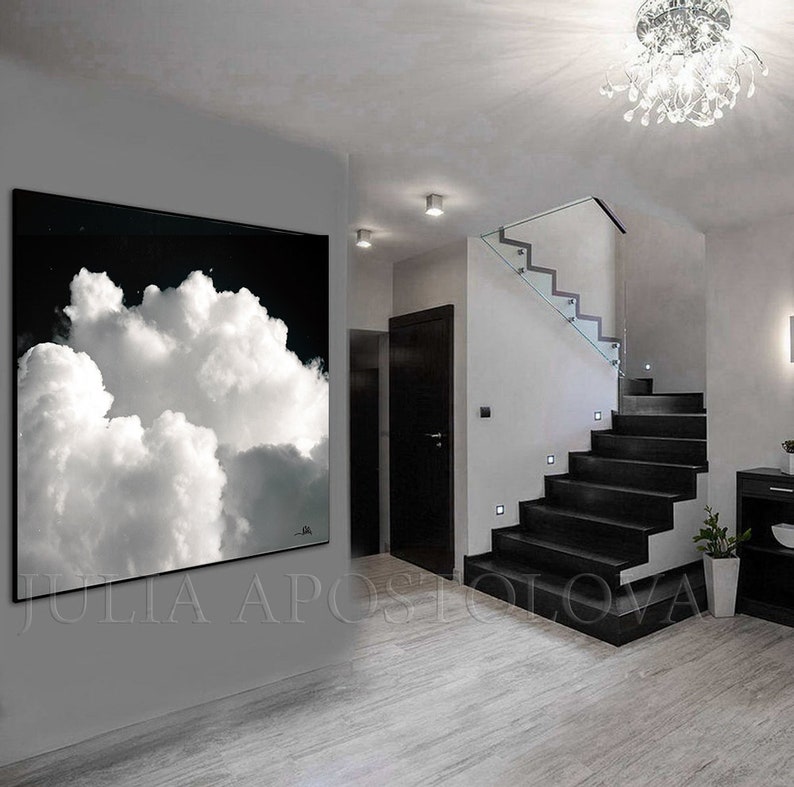 May include: Large black and white cloud art print. The artwork features a dramatic image of fluffy white clouds against a dark background. The print is displayed in a modern interior setting, enhancing the room's aesthetic.