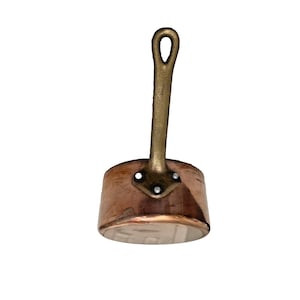 May include: A copper saucepan with a brass handle. The handle is attached with rivets. The pot has a rounded base and a slightly flared rim. The copper has a warm, reddish-brown colour.