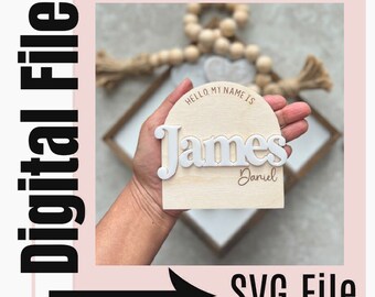 Puede incluir: Un arco de madera con el texto "Hola, mi nombre es" y el nombre "James Daniel" escrito en letras blancas y doradas.