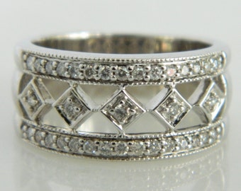 May include: A silver band ring with a delicate design featuring three rows of small diamonds and a central row of larger diamonds set in a geometric pattern.