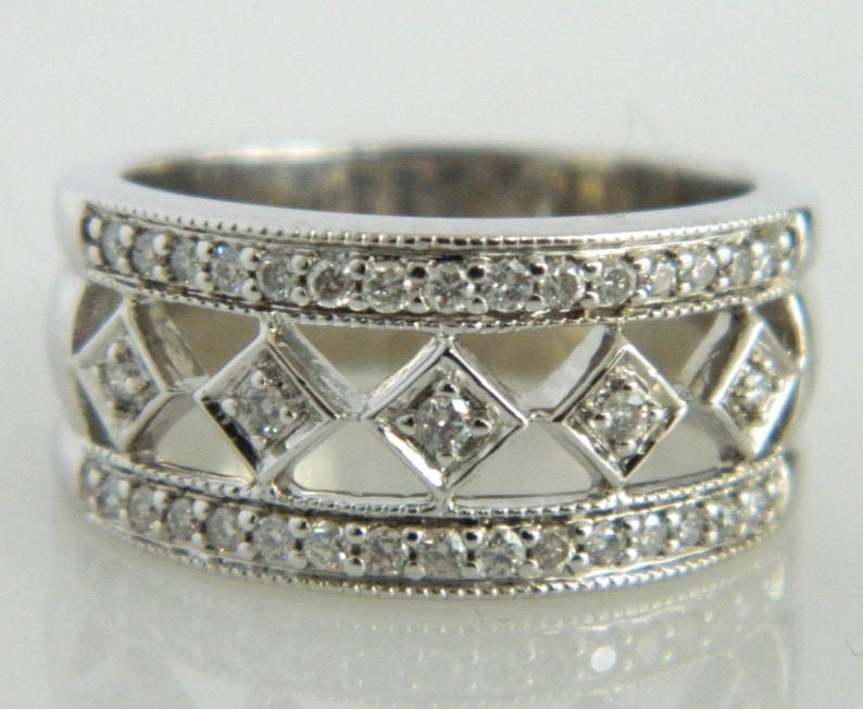 Pu&ograve; includere: Un anello d'argento con tre file di piccoli diamanti. La fila centrale presenta un design geometrico con accenti di diamanti.