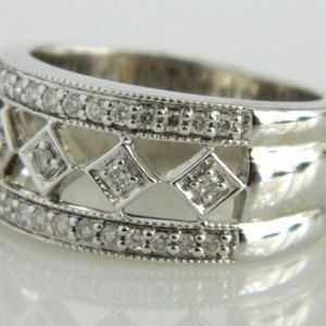 Pu&ograve; includere: Un anello a fascia d'argento con un designo tempestato di diamanti. L'anello presenta un delicato motivo traforato con pi&ugrave; file di piccoli diamanti.