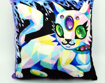 May include: Square pillow featuring a geometric design of a cat-like creature with large green eyes and a purple gem. The pillow has a black background with a starry sky design on the edges. The creature is primarily white, blue, and yellow.