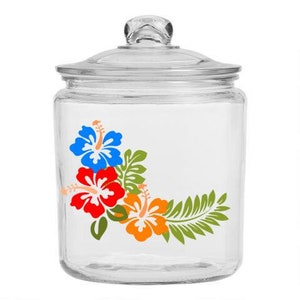 May include: A clear glass jar with a lid, decorated with a floral design featuring red, blue, and orange hibiscus flowers and green leaves.