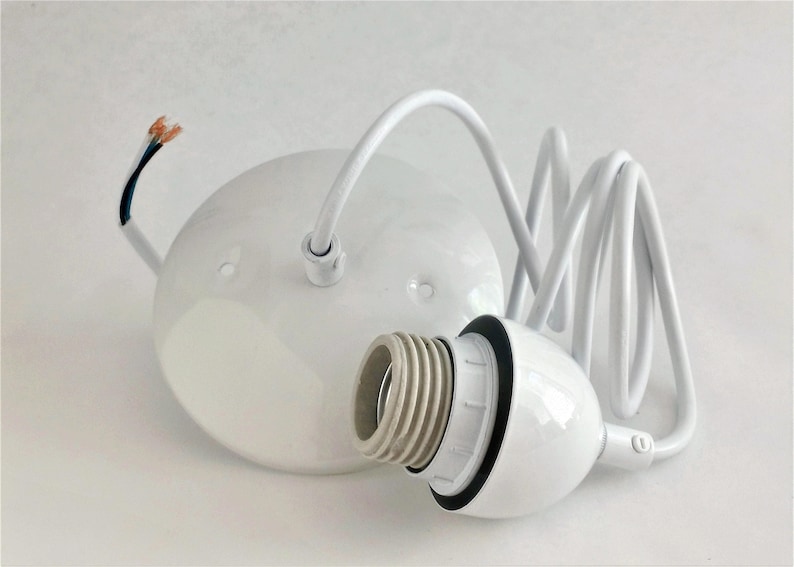 May include: White ceramic ceiling light fixture with a white cord and a white socket. The cord is coiled and the socket is attached to a white ceramic base.