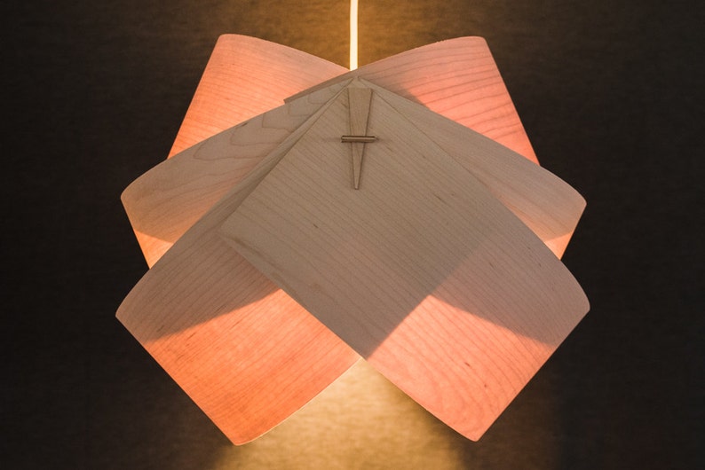 May include: A light wood pendant lamp with a geometric design. The lamp is made of multiple pieces of wood that are joined together to create a unique and modern look.